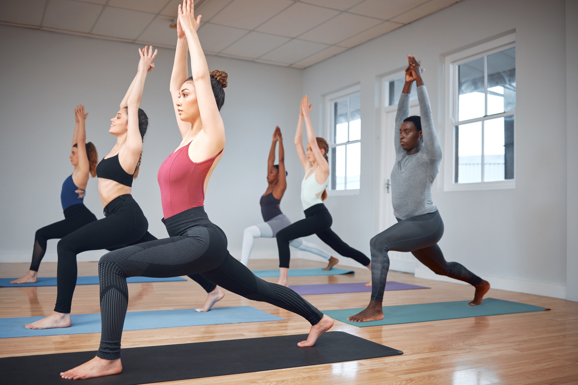 Shot of a group of yoga students completing lunges into the warrior pose during a class